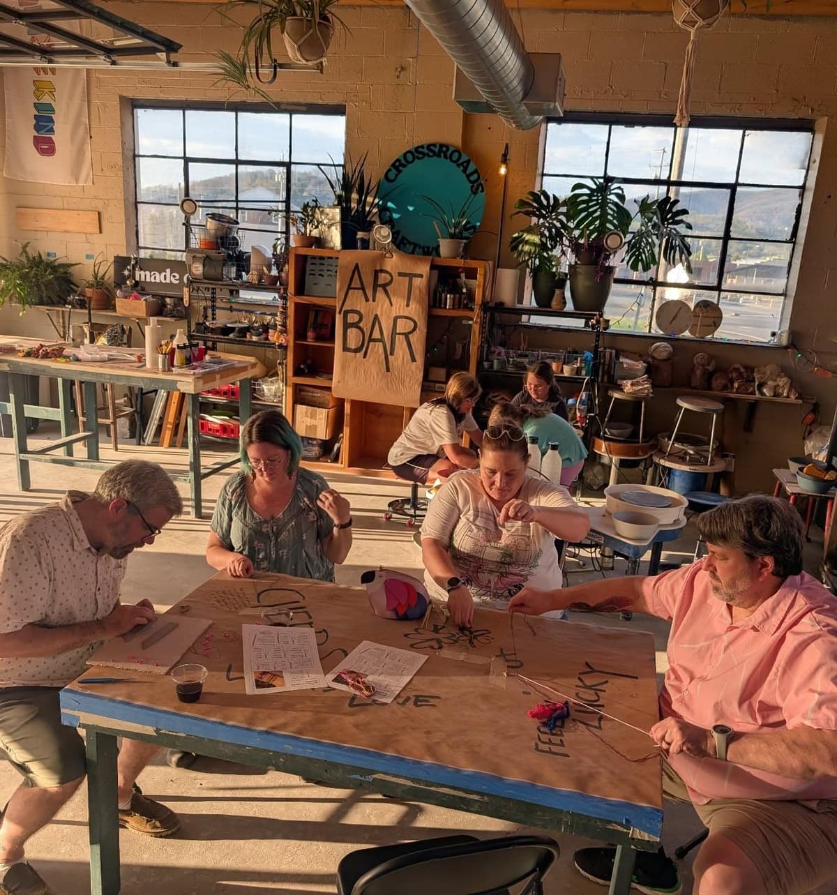 A long studio table prepared for an Art Bar class or event.