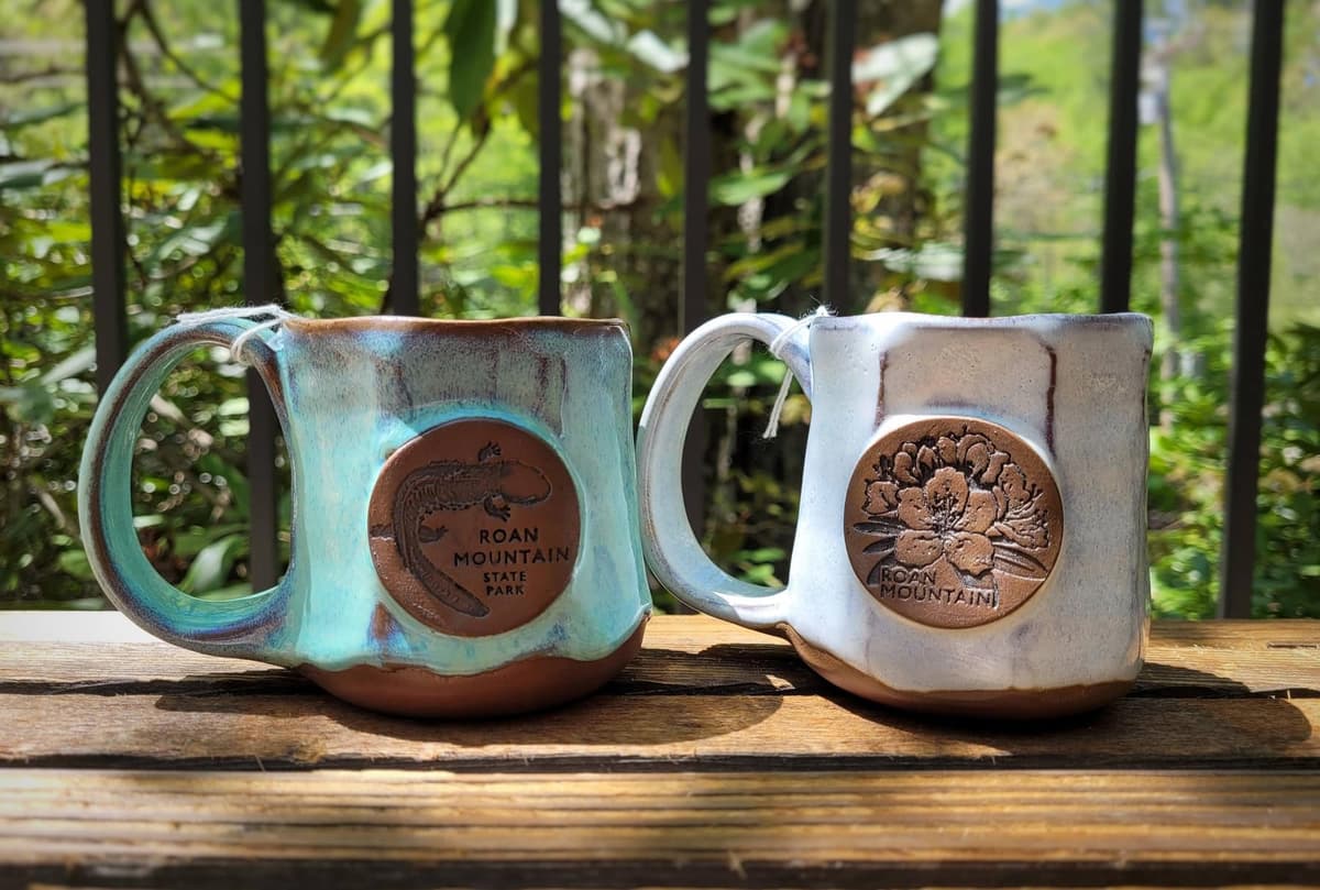 Two handmade Roan Mountain mugs displayed outdoors.